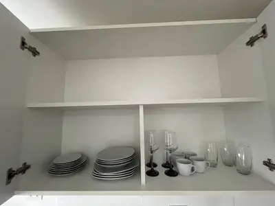 a white kitchen with plates and glasses on a shelf at Entire apartment minutes from Miraflores in Lima