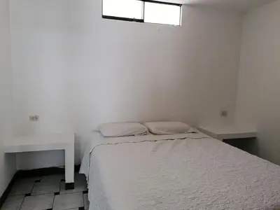 a white bedroom with a bed and a window at Casa de Playa en Lobos in Cerro Azul