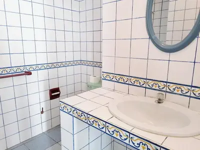 a white tiled bathroom with a sink and a mirror at Casa de Playa en Lobos in Cerro Azul