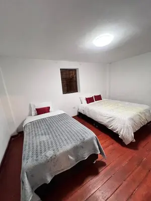 two beds in a room with wooden floors at SkyGuest Cusco San Cristobal in Cusco