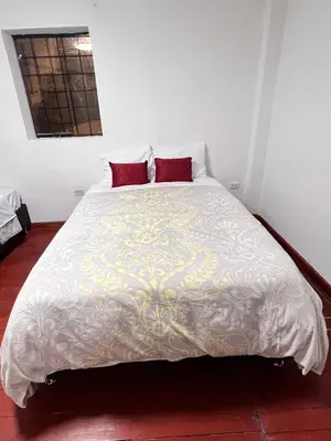a bedroom with a large white bed with two red pillows at SkyGuest Cusco San Cristobal in Cusco