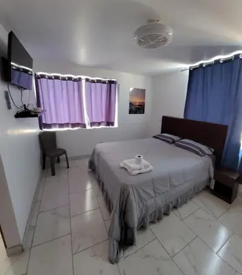 a bedroom with a bed with purple curtains at Bravos Hospedaje Punta Negra in Punta Negra