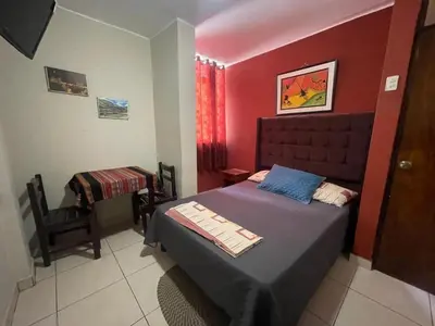 a bedroom with a bed and a table and a chair at Hospedaje Mayo Huacachina in Ica
