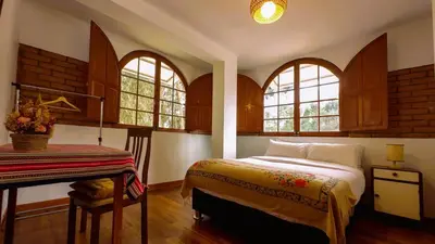 a bedroom with a bed and a desk and windows at Fundo Venegas & Montoya in Jauja