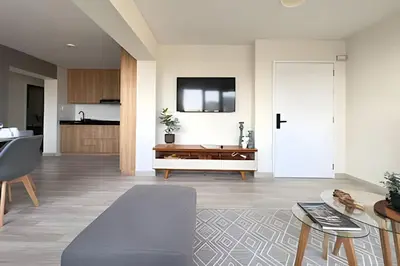a living room with a table and a tv on the wall at The 28 Residence Miraflores in Lima