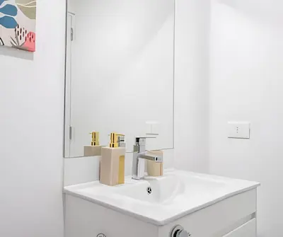 a white bathroom with a sink and a mirror at The Urban Loft in San Miguel in Lima