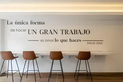 a white wall with a sign on it with three stools at The Urban Loft in San Miguel in Lima