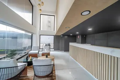 an office lobby with white chairs and a table at The Urban Loft in San Miguel in Lima