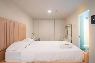 a bedroom with a large white bed and a bathroom at The Urban Loft in San Miguel in Lima