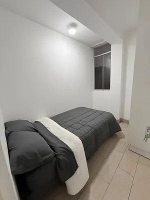 a white bedroom with a bed with a black blanket at Apartamento moderno a 5 minutos de Plaza Norte in Lima