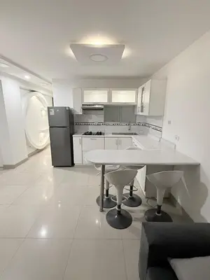 a white kitchen with a table and a refrigerator at Apartamento moderno a 5 minutos de Plaza Norte in Lima