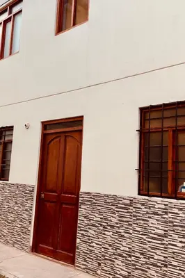 a white building with a red door and two windows at Tampumachay in Cusco