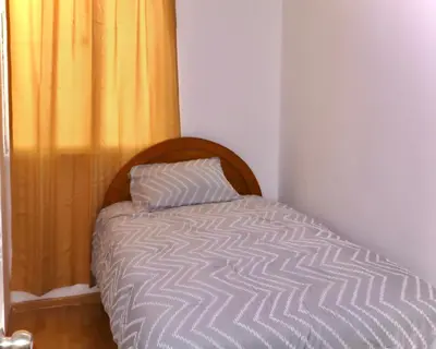 a bed with a wooden headboard and a yellow curtain at Lindo depa cerca a huacachina in Ica