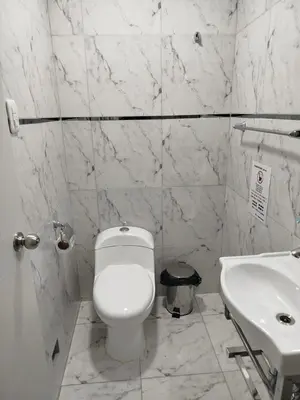 a white bathroom with a toilet and a sink at Hostal San Ignacio Monterrico in Lima
