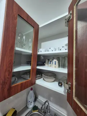 a kitchen cabinet with dishes on shelves above a sink at Luna Room in Lima