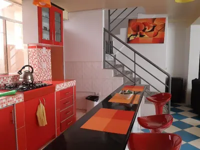 a kitchen with red cabinets and a staircase with red stools at Departamento turístico Rosaelena b&b 9 personas in Cusco