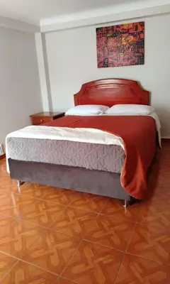 a bedroom with a large bed with red sheets at Inkas Hotel Cusco in Cusco