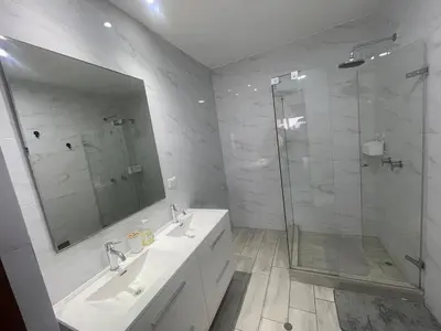 a bathroom with two sinks and a glass shower at Penthouse con Vista al Mar in Lima