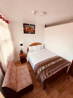 a bedroom with a large bed and a table at Pakari wasi inn in Cusco