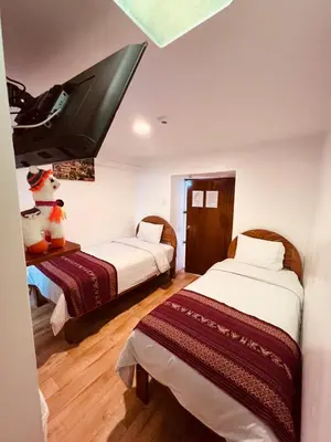 a room with two beds and a flat screen tv at Pakari wasi inn in Cusco