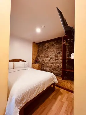 a bedroom with a bed and a stone wall at Pakari wasi inn in Cusco