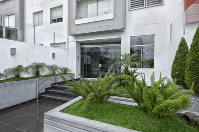 a white building with plants in front of it at Guernica Apartments in Lima