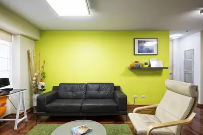 a living room with a black couch and a yellow wall at La Masia Apartments in Lima