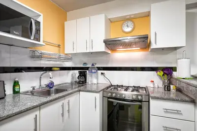 a kitchen with white cabinets and a stove top oven at La Masia Apartments in Lima