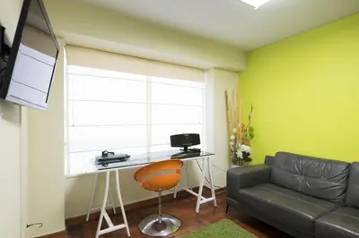 a living room with a couch and a desk at La Masia Apartments in Lima