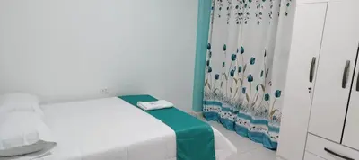 a small room with a bed and a curtain at Hospedaje Bella Acuarela in Oxapampa