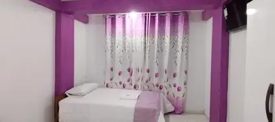 a small room with a bed and purple curtains at Hospedaje Bella Acuarela in Oxapampa