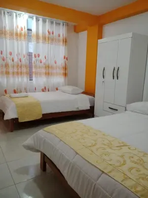 a bedroom with two beds and a dresser at Hospedaje Bella Acuarela in Oxapampa