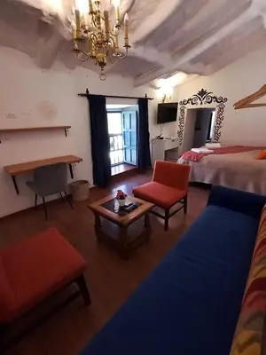 a room with two beds and a couch and a table at Apartamento Familiar con balcón y vista a la Ciudad, Centro in Cusco