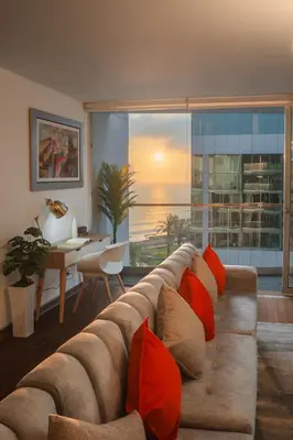 a living room with a couch with red pillows at Espectacular vista al mar en Miraflores in Lima