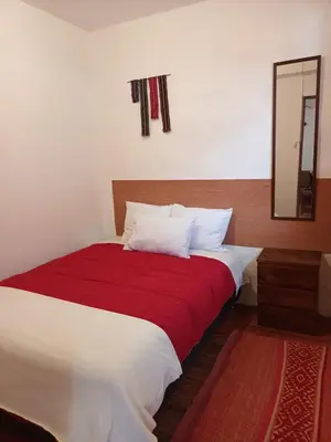 a bedroom with a red and white bed with a mirror at Yuraq Wasicha in Cusco