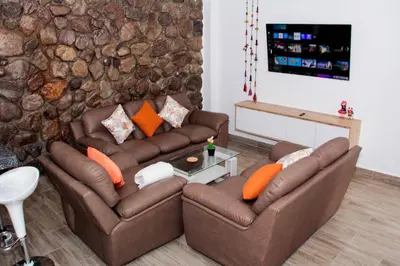 a living room with two brown couches and a tv at Valle Sagrado Mágico in Urubamba