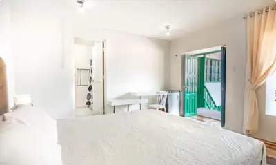a bedroom with a white bed and a green door at Corazón de Cusco 2 in Cusco