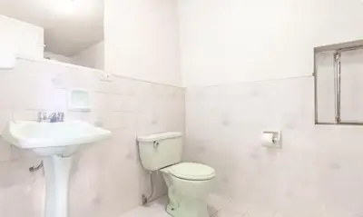 a white bathroom with a toilet and a sink at Corazón de Cusco 2 in Cusco