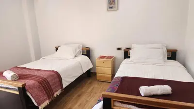 a bedroom with two beds and a night stand with a drawer at Chakana Wasi in Calca