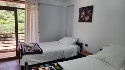 a bedroom with two beds and a window with a balcony at Chakana Wasi in Calca