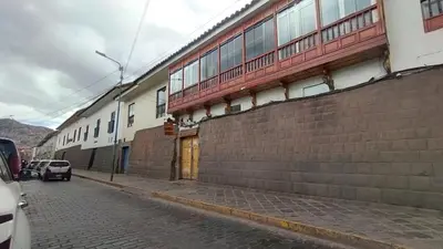 a building with a brick wall next to a street at Maruri Valentino apartment in Cusco