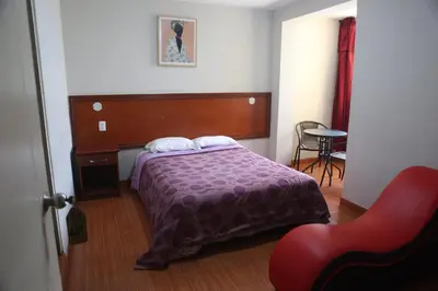a bedroom with a bed and a red chair at Hostal Real in Lima