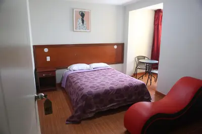 a bedroom with a bed and a red chair at Hostal Real in Lima
