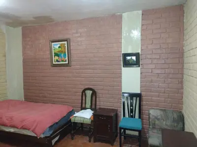 a bedroom with a brick wall with a bed and two chairs at Cozy Rural House in Apata - Jauja