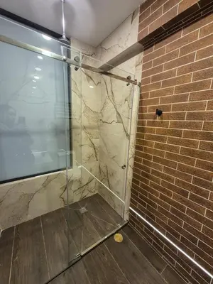a shower with a glass door next to a brick wall at Hotel Zaniah in Huancayo