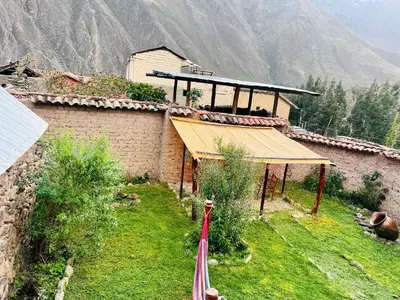 a building on top of a hill with mountains in the background at Stone house in Ollantaytambo in Ollantaytambo