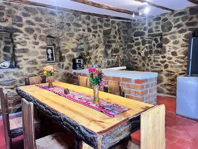 a wooden table with flowers in a room with stone walls at Stone house in Ollantaytambo in Ollantaytambo