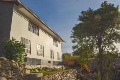 a building with a stone wall next to a tree at La Casa de Toño in Huancayo