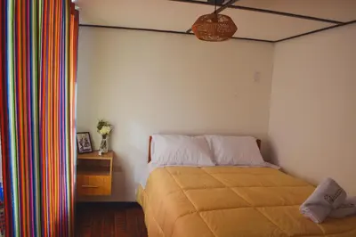 a bedroom with a bed and a table with a lamp at La Casa de Toño in Huancayo