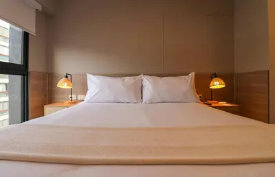 a bedroom with a large white bed with two lamps at Schell in Miraflores by Wynwood House in Lima